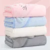 Toallas con capucha dobladas en rosado, celeste, blanco y gris, apiladas para mostrar las opciones de color.